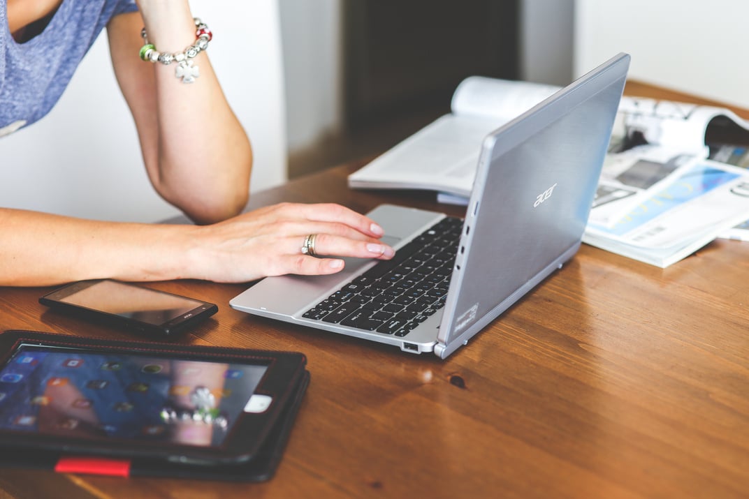 Close-up of woman typing on keyboard of laptop